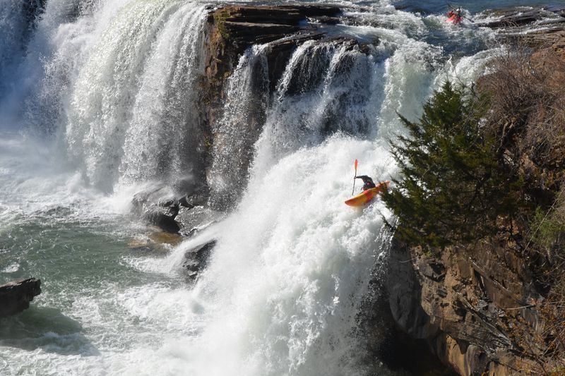a man riding a wave on top of a waterfall