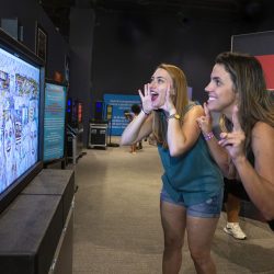 Two visitors play with an interactive digital display at a children's science center STEM exhibit