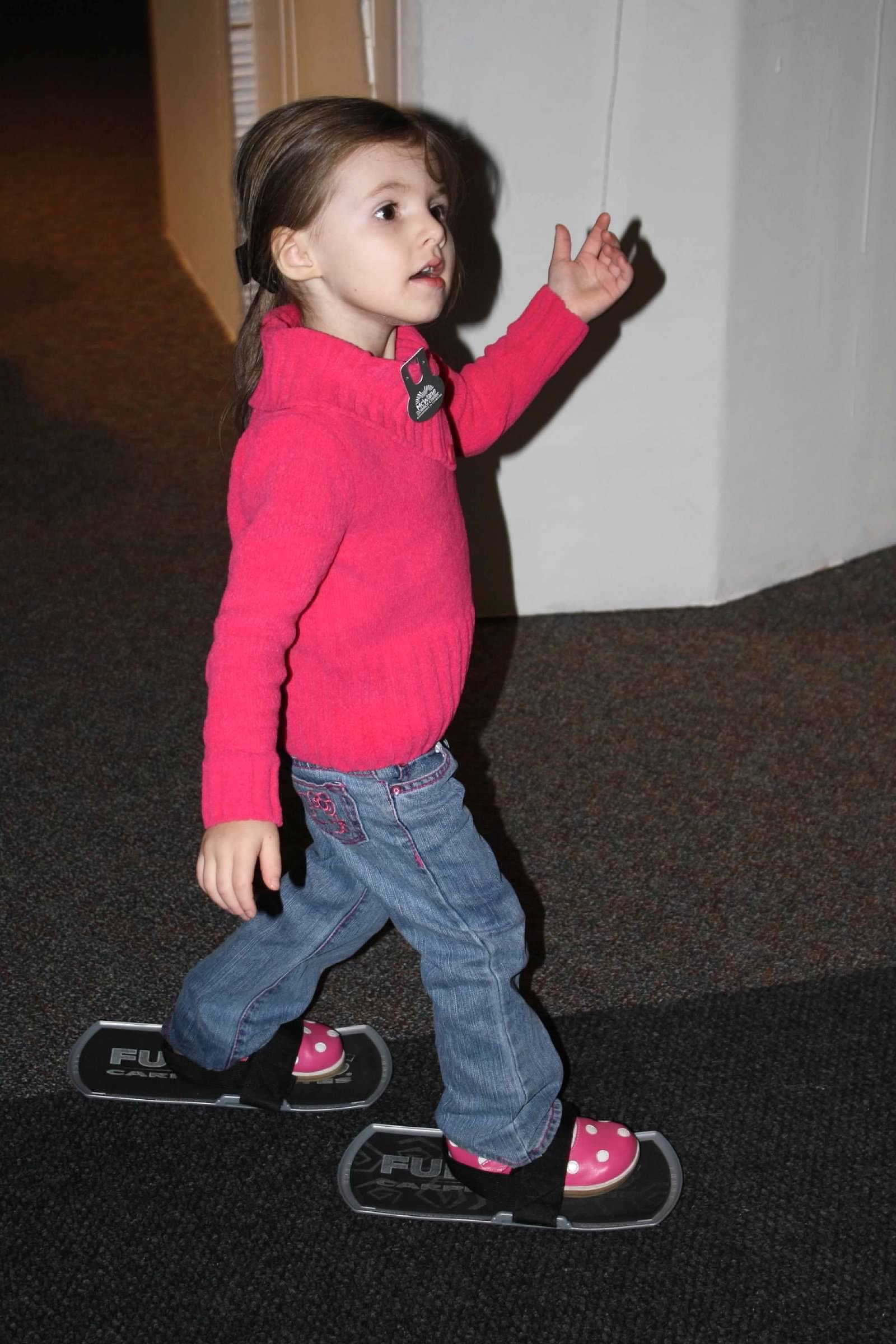 Child tests friction with carpet skates at children's science center hands-on exhibit.