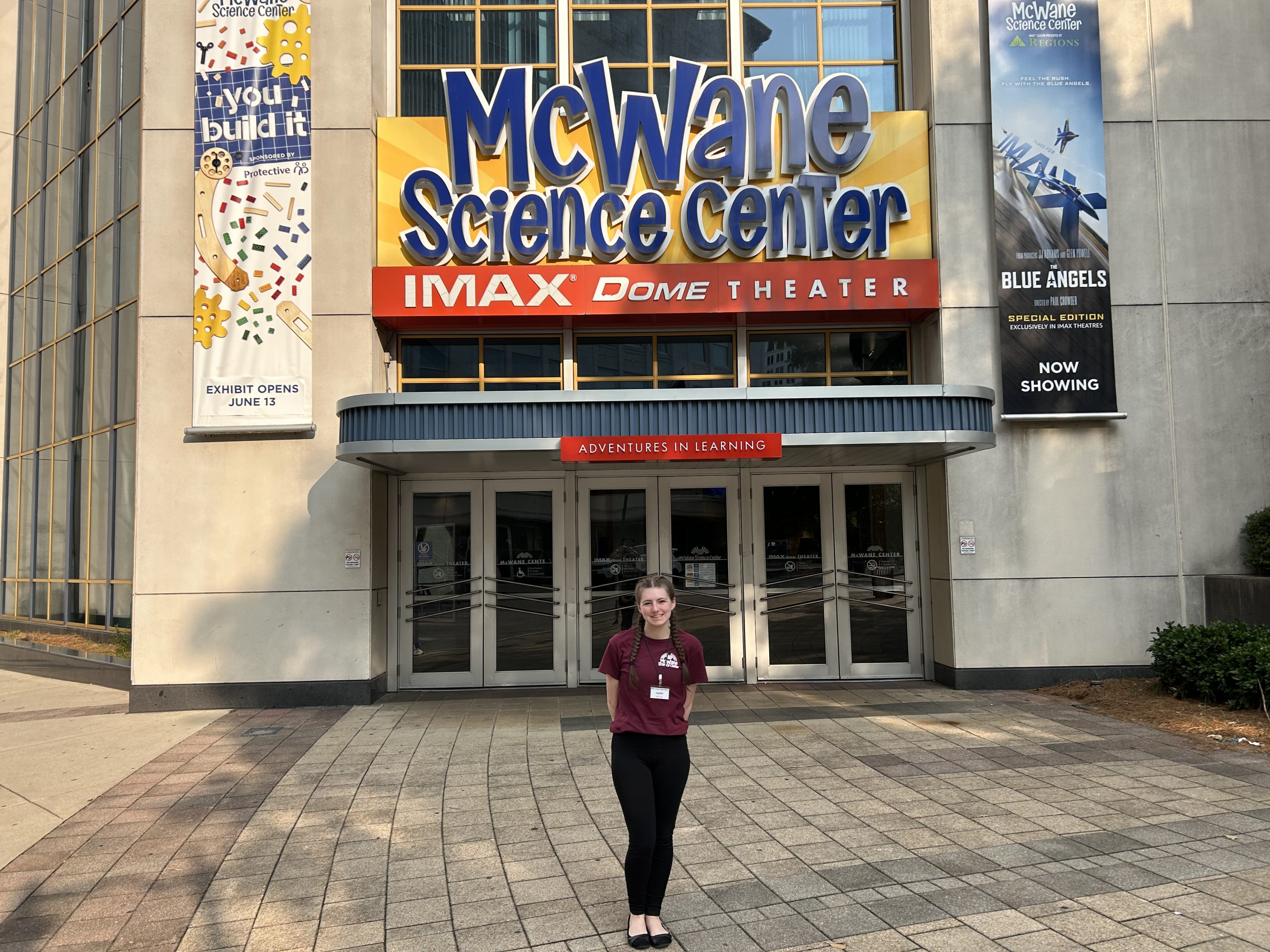 McWane Science Center entrance and IMAX Dome Theater, with a staff member welcoming families to hands-on children's STEM fun.